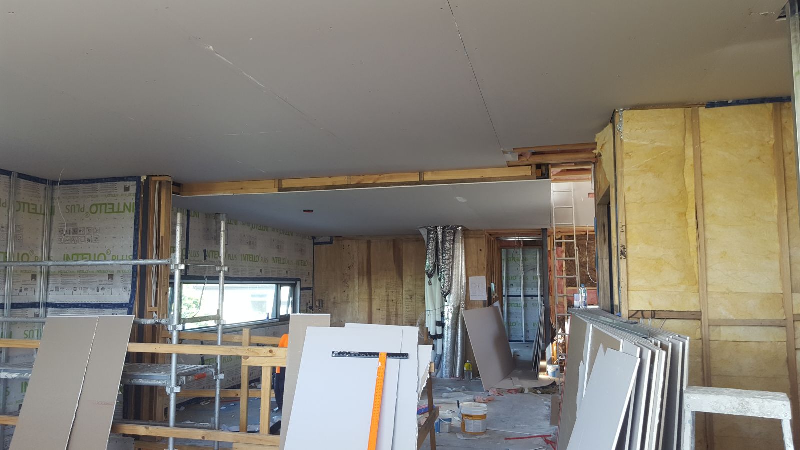 Ceiling plasterboard being installed with membrane and ductwork still visible